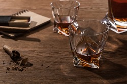 Selective focus of brandy in glasses with cigars, lighter and matches on wooden table,stock photo