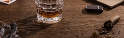 Glass of brandy with cigar, lighter and book on wooden table, panoramic shot,stock photo