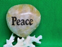 Cute little zen rock that says PEACE sitting on a solid green background. Massage, relaxing, comforting wallpaper