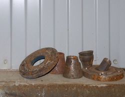 Old rusty steel products on slightly blurred gray background of wall. Flange, cone, pipe with thread. Texture of rusty metal. Composition with rusty iron. Free space for design. 
