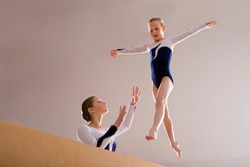 Low angle view of a gymnastics instructor teaching girl on a balance beam.