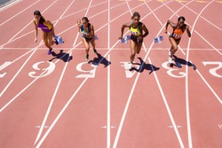 Female athletes setting off from their starting blocks at the start of a sprint race at an athletics competition at the track