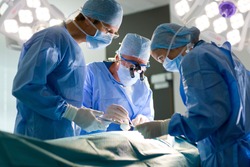 A team of experienced surgeons performing a complex operation with full concentration in well-lit operating room