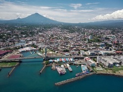 Manado City, North Sulawesi Province, Indonesia. the view from above with the boat harbor, the landmark of the Soekarno bridge, and the background of Mount Klabat.