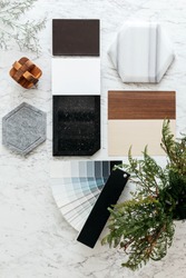 Top view of Material Selections including Granite tile, Marble tile, Acoustic tile, Walnut and Ash Wood Laminate and Painted color swatch with plant and flowers on marble top table.