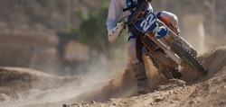 Racer boy on motorcycle participates in motocross race, active extreme sport, flying debris from a motocross in dirt track