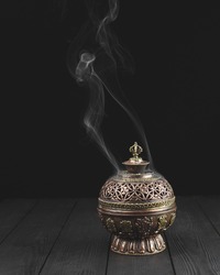 Copper incense holder on dark wooden background bukhoor burner white smoke smoldering