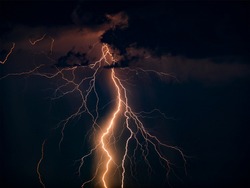 There are many lightning bolts against the black sky. Night photo of a thunderstorm on a long exposure, close up. A composite image of several frames. Copy space, an effect for design and overlay.