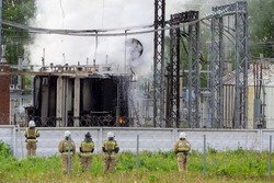Five firefighters are looking at an open fire. Short circuit at the power plant. Extinguishing a fire with foam at a city electrical substation. Inscription on the back: 