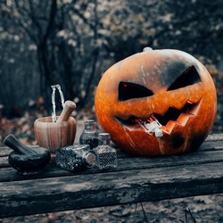 Halloween pumpkin in the form of Jack's lantern in the dark forest. Witchcraft tools.