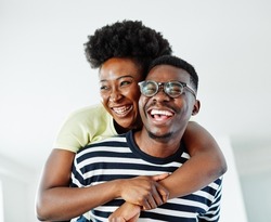 Portrait of a lovely young couple having fun and laughing together piggyback at home