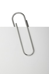 close up of  a metal paper clip and paper on white background
