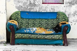 an old blue green sofa that has been damaged in front of the house