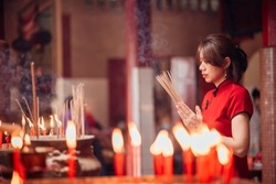 An Asian woman lighting incense sticks to pay homage to the Chinese New Year.
