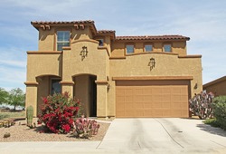 New two-story, brown and tan beige stucco home in Tucson, Arizona, USA with beautiful blue sky and landscaping.