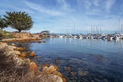 Historic Monterey Harbor and Marina; moored & anchored colorful sailboats, yachts, and speed boats. Located in the Monterey Bay National Marine Sanctuary, on California Central Coast, near Big Sur.