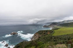El Nino storm, fog, and gray skies on Highway 1, with aquamarine waters & rock formations, along the rugged Big Sur coastline, near Carmel and Monterey, CA. on the California Central Coast.