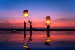Fisherman family are flying lantern on the boat in the Mekong river During the twilight at beautiful sunset, silhouette with copy space.