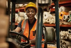 Portrait of a young African female forklift operator moving boxes around a textile warehouse