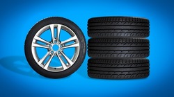 Set of four wheels on blue background. New tires on aluminum wheel rims. No logo visible, only tire labeling visible.