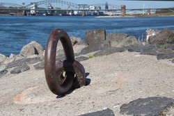 Rusted steel ring for fastening large ships on the Rhine in Cologne Poll with a view of the south bridge and Cologne Cathedral.
