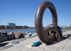 View of an upstanding rusted steel ring on the banks of the Rhine in Cologne Poll. Two parked trucks can also be seen in the close-up.
blue sky