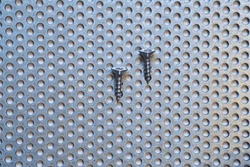 two self-tapping screws on a perforated sheet steel with round holes, galvanized, rust-free,