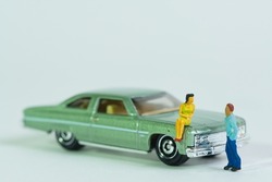 a couple meets at a vintage car, the woman sits on the fender, miniature figures scene, toy cars,