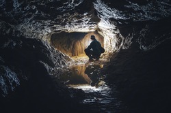man exploring cave colorful light