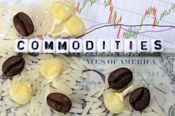 Coffee bean, rice, corn and letter cube on dollar and candle stick chart background. Conceptual image of commodity trading.