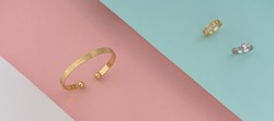 Golden bracelet and and white gold ring with diamonds on colorful background