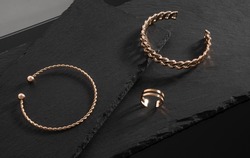 Chain and spiral shape bracelets and Gold ring on black stone trays with copy space