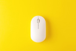 White wireless mouse on yellow background, minimal, flatlay