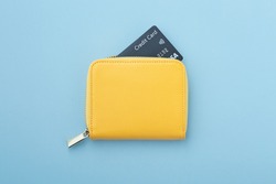 Credit card in yellow wallet on blue background, top view