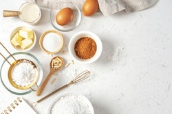 Baking pastry or cake ingredients, brown sugar, butter, flour, eggs and milk with utensil on marble table, top view with copy space