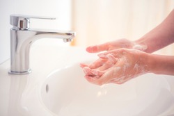 Washing hands with soap under the faucet with water. Hygiene concept.