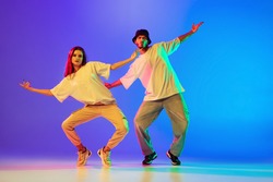 Knee movements. Two young people, guy and girl, dancing contemporary dance, hip-hop over blue background in neon light. Modern dance aesthetics concept. Copyspace for ad.