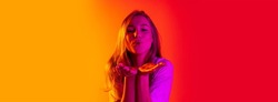 Kiss blowing. Blowing kliss. Young atractive caucasian girl giving air kiss isolated on yellow red background. Youth culture. Concept of happiness, greetings, emotions, feeling expression, ad