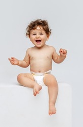 Smiling happy child. Portrait of little toddler boy, baby in diaper joyfully sitting and laughing isolated on white studio background. Concept of childhood, motherhood, life, birth. Copy space for ad
