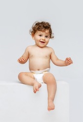 Smiling happy child. Portrait of little toddler boy, baby in diaper joyfully sitting and laughing isolated on white studio background. Concept of childhood, motherhood, life, birth. Copy space for ad