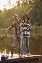 Sunset aesthetics. Young beautiful couple spending time in nature, near river and fishing. Nice summer weekend. Fresh air breathing, having fun. Concept of leisure time, relationship, fun, ad