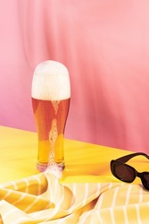 Glass of chill foamy lager beer isolated over pink yellow background. Summer pool party. Vacation. Concept of cocktails, alcoholic drinks, taste, party, mix. Copy space for ad. Retro style