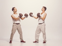 Portrait of two men playing, boxing in gloves isolated over grey studio background. Funny image of two friends . Concept of sport, hobby, work, active lifestyle, retro fashion. Copy space for ad