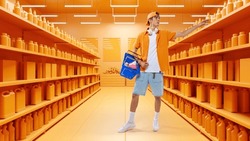 Young student in casual clothes holding cartboard box went out window shopping. Black Friday sales. 3D model of supermarket. Concept of shopping, hypermarket, purchasing. Copy space for ad