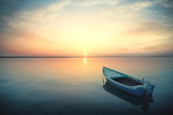 Canoe floating on the calm water under amazing sunset