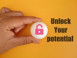 Hand holding white ball with icon padlock and text Unlock your potential on orange background 