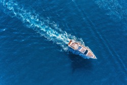 Yacht at the sea in Europe. Aerial view of luxury floating ship at sunset. Colorful landscape with boat in marina bay, blue sea. Top view from drone of yacht. Luxury cruise. Seascape with motorboat