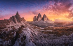 Mountains and beautiful sky with colorful clouds at sunset Autumn landscape with mountains, stones, grass, trails, blue sky with red and orange clouds. High rocks. Tre Cime in Dolomites, Italy. Travel