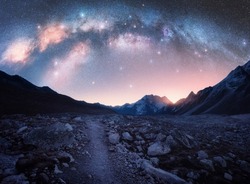 Arched Milky Way and mountains at night. Beautiful landscape with bright milky way arch, rocky path, starry sky at night in Nepal. Trail in mountain valley, sky with stars at sunrise. Himalayas. Space
