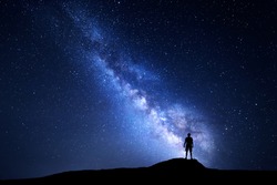 Milky Way. Beautiful night sky with stars and silhouette of a standing alone man on the mountain. Blue milky way with man on the hill. Background with galaxy and silhouette of a man. Universe